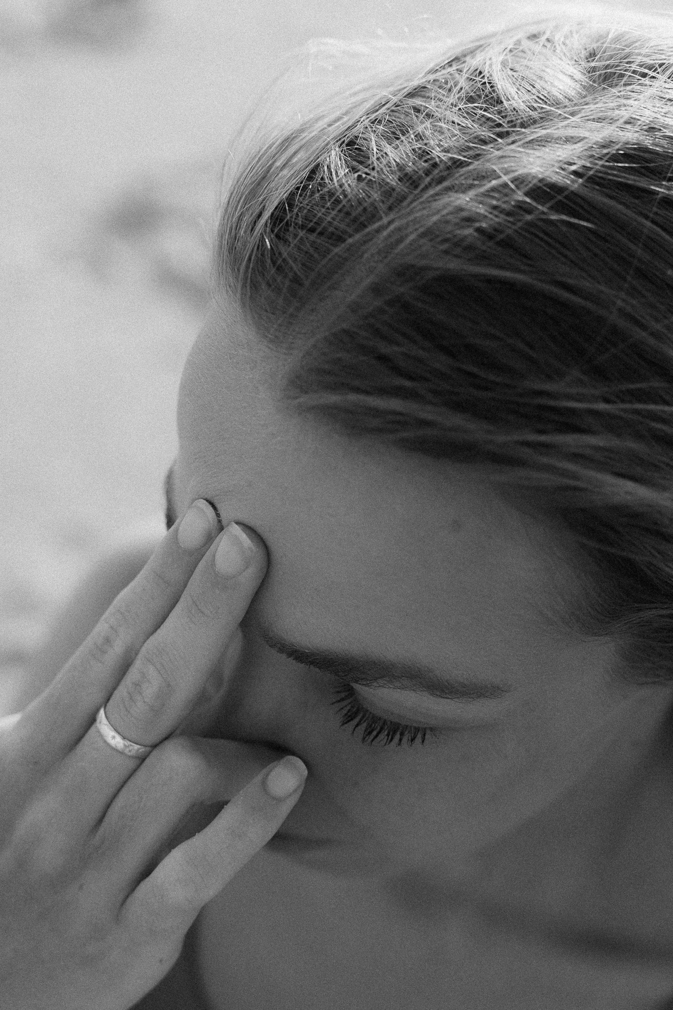 A woman covering her face with her hand, her worry visible, black and white film photograph.