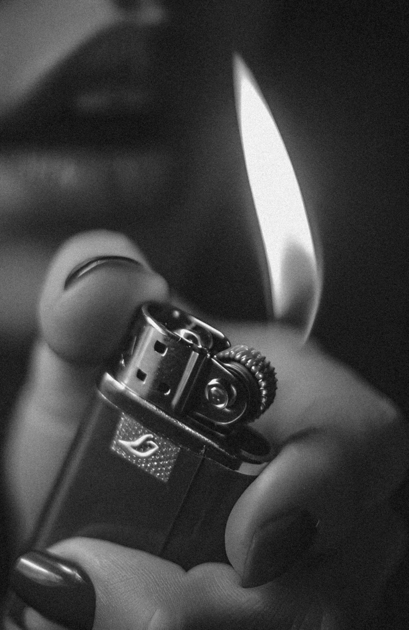 A hand holding a lit lighter, close up, black and white film photograph.